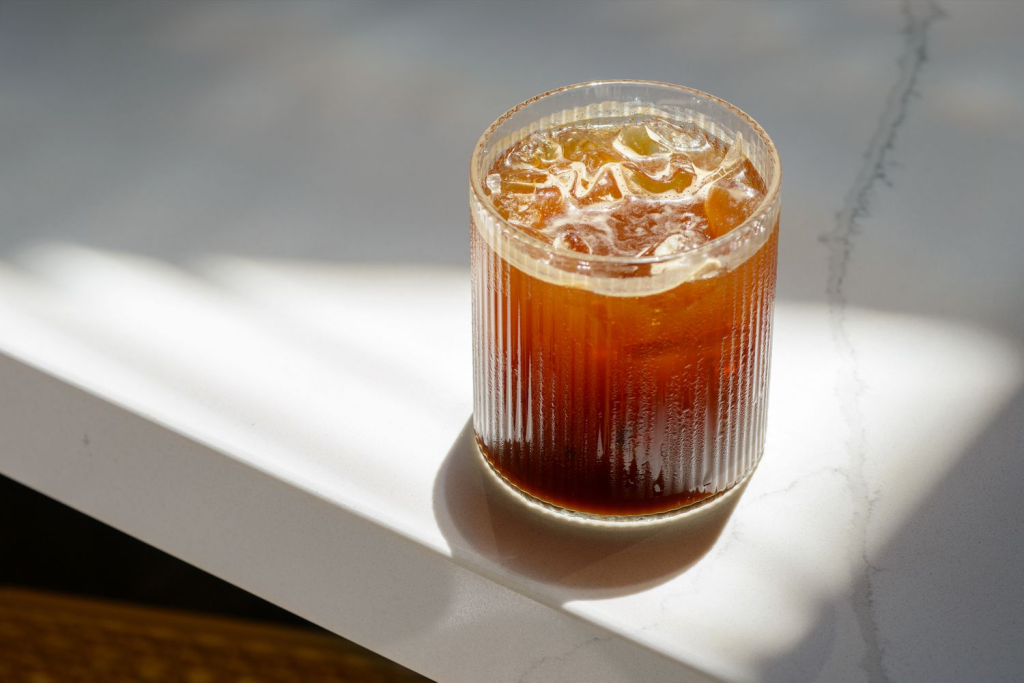 Menikmati kesegaran segelas es Americano di coffee shop terdekat dengan suasana yang nyaman.